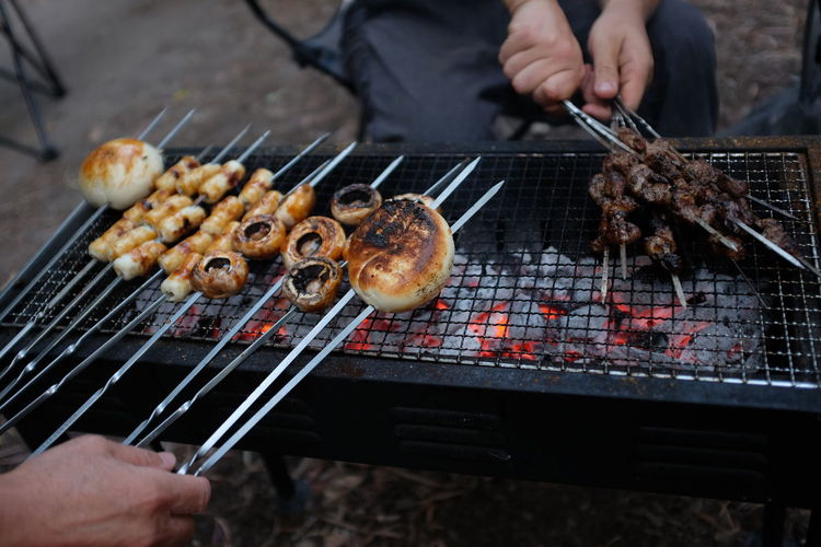 Friends preparing meat on barbecue grill