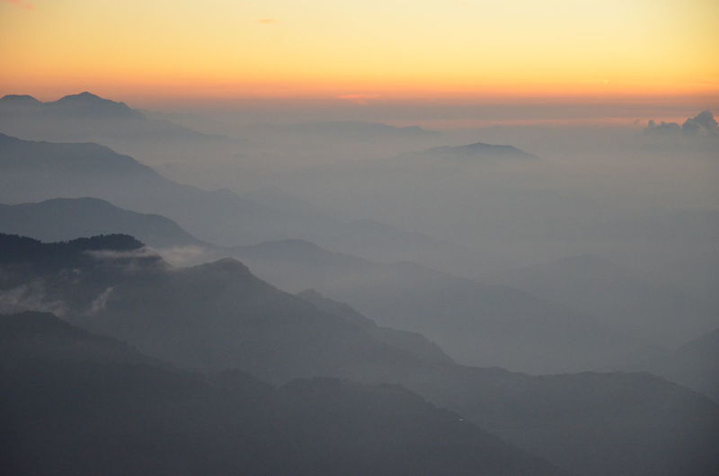 Scenic view of silhouette mountains in foggy weather sunrise