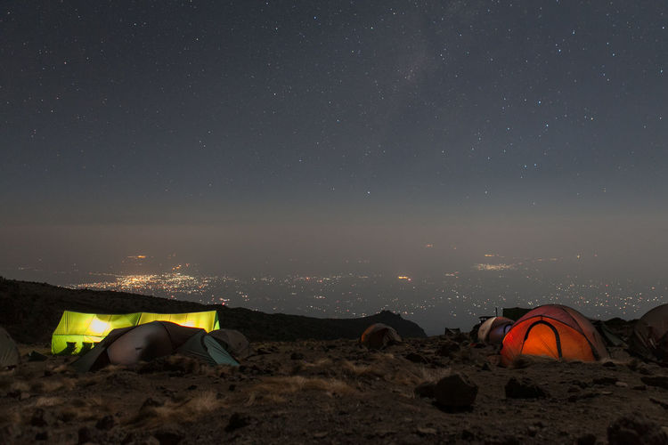 Tents on mountain against sky at night