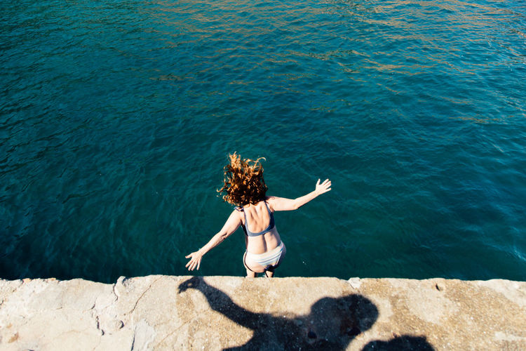 High angle view of woman jumping in the sea