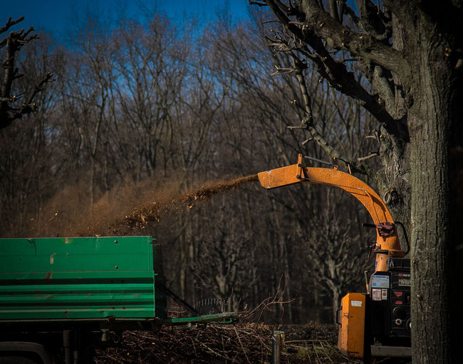 Gardening equipment spraying dirt against trees on field