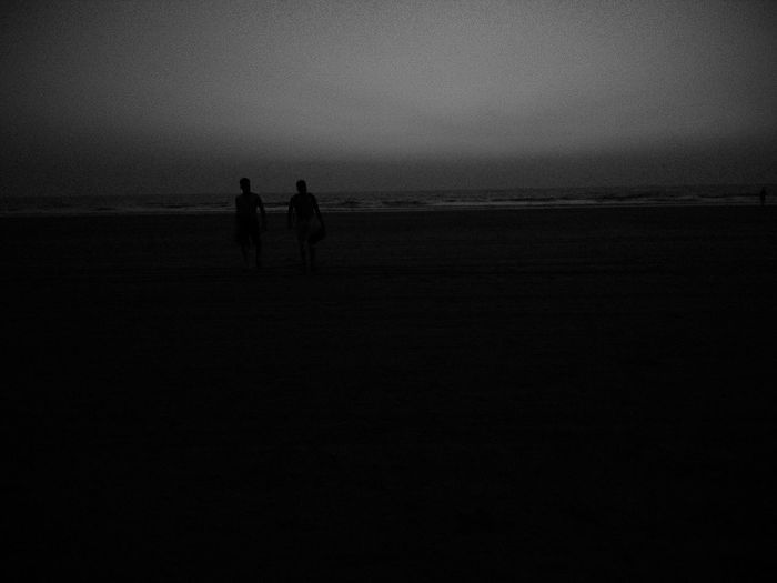 Silhouette people on beach against sky during sunset