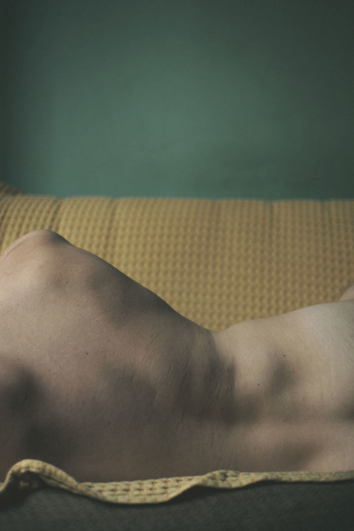 Midsection rear view of shirtless man sleeping on sofa at home