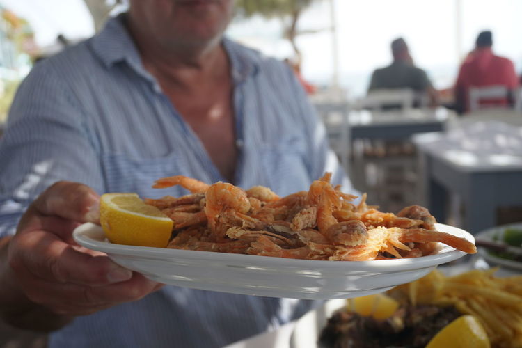 Midsection of man holding seafood in plate