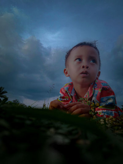 Portrait of cute boy looking away against sky