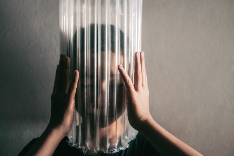 MIDSECTION OF WOMAN TOUCHING GLASS AGAINST WALL AT HOME