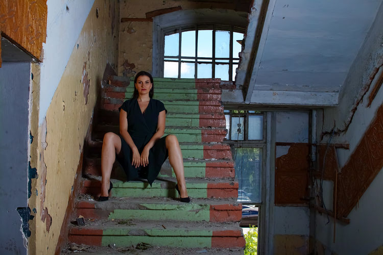 Portrait of young woman sitting in abandoned building