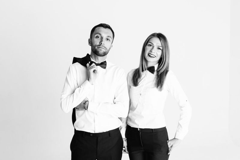 Portrait of confident elegant couple standing against white background