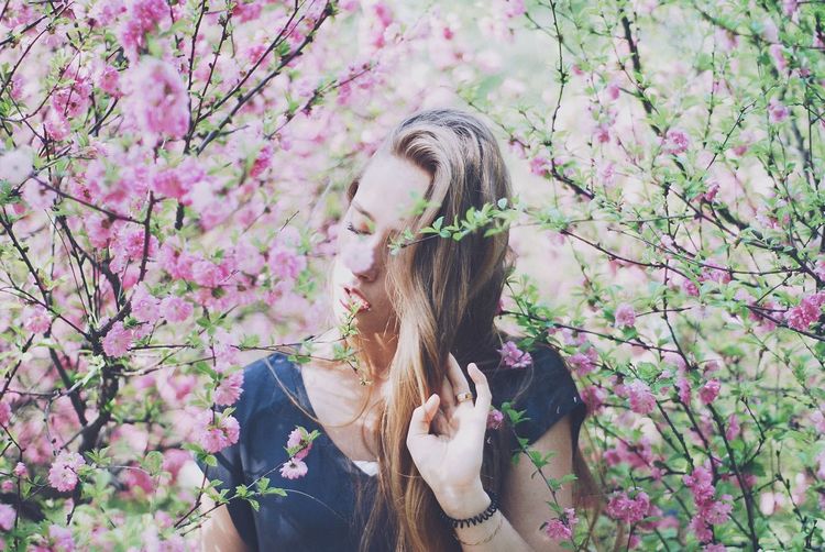 Low angle view of woman by pink flowering tree