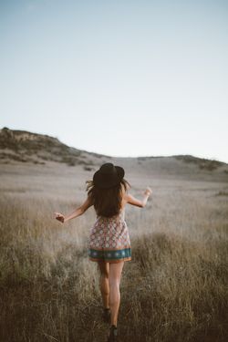 Rear view of woman walking on field against clear sky