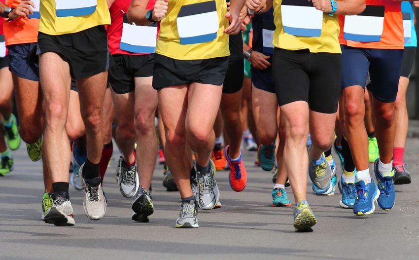 Low section of male athletes running marathon on road