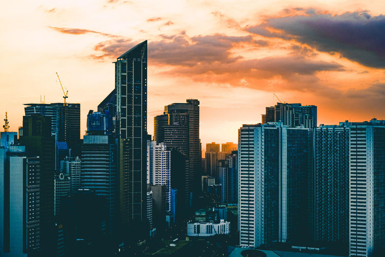Modern buildings in city against sky during sunset