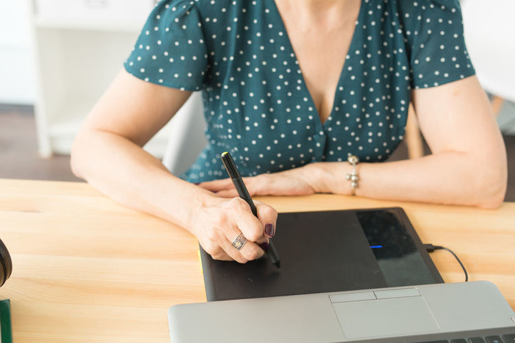 Midsection of woman using mobile phone while sitting on table