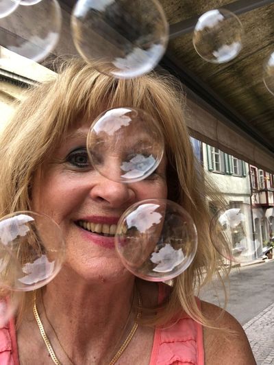 Portrait of smiling woman by bubbles in city