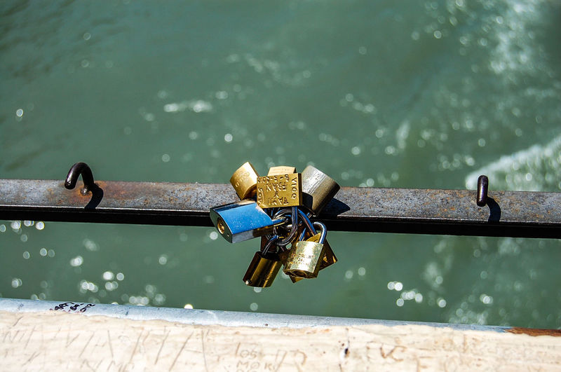Close-up of padlocks on railing by river