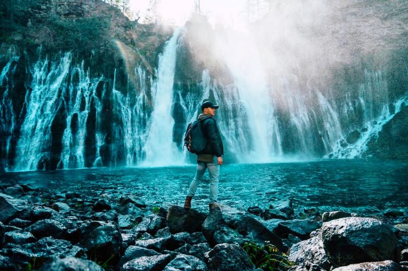 Man standing on rock looking at waterfall in forest