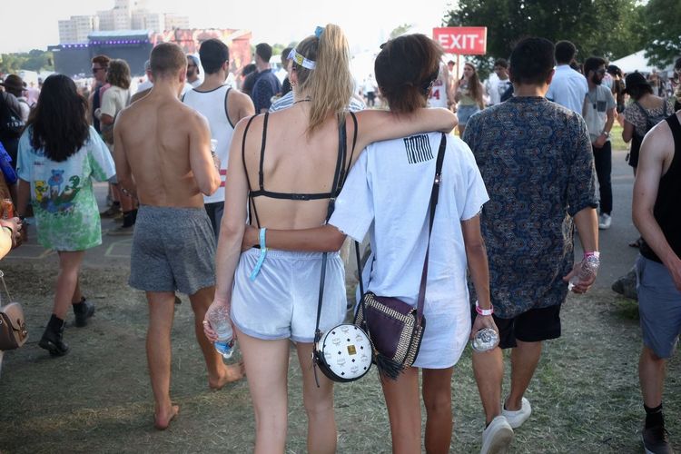 Rear view of two girls walking together at music festival