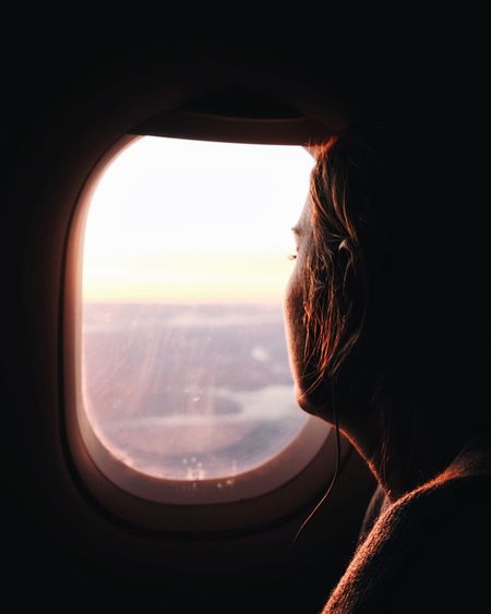 Rear view of man looking through airplane window