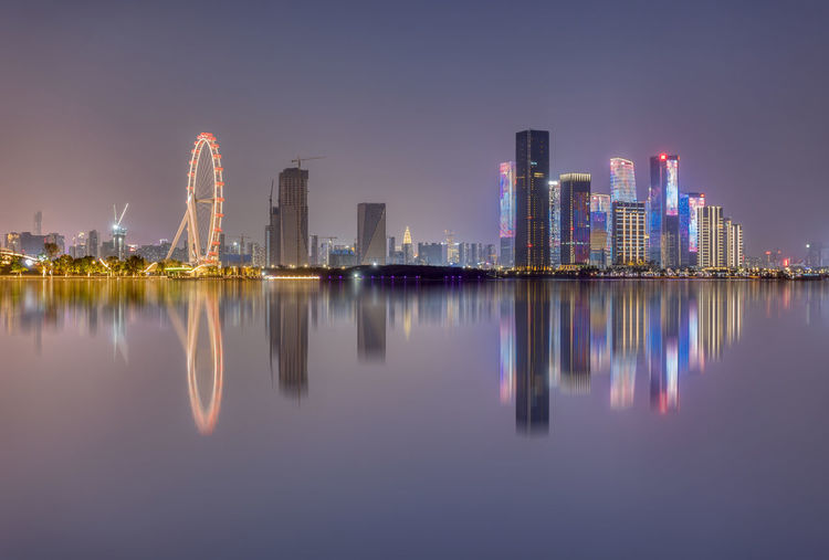 Reflection of illuminated buildings in city against sky