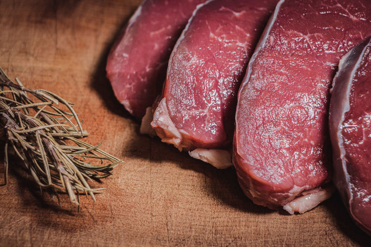 Cuts of argentine beef on wooden board along with rosemary