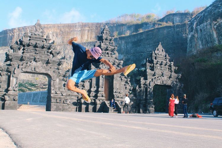 Young man breakdancing on road in front of gate
