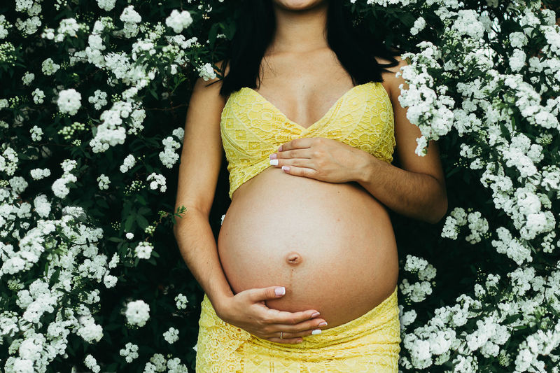 Midsection of pregnant woman lying down on flowers