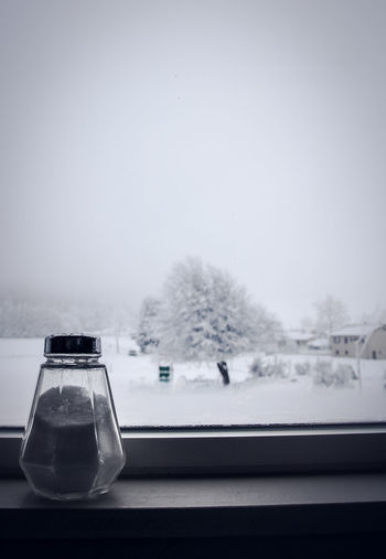 Close-up of salt shaker on window sill during winter