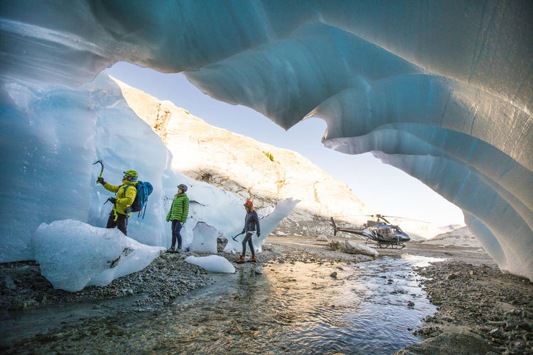 Mountain guide brings two female clients into ice cave to go climbing.