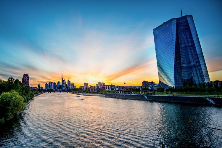 View of modern buildings by river against sky during sunset in frankfurt, germany 