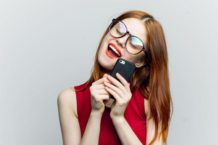 Portrait of young woman using phone against white background