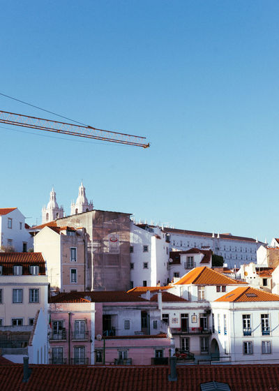 Buildings in city against clear blue sky