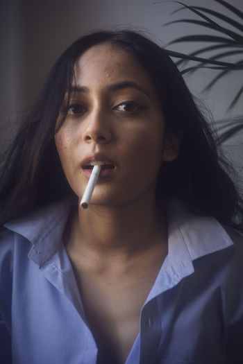 Close-up portrait of a young woman holding cigarette