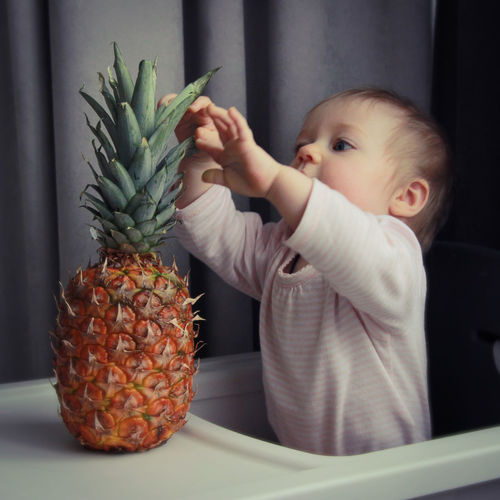 Baby girl holding pineapple fruit 