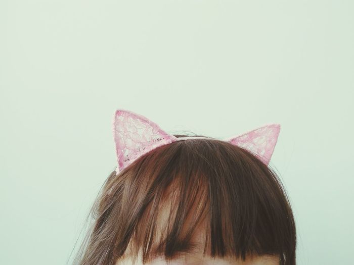 Close-up of girl wearing headband against white background