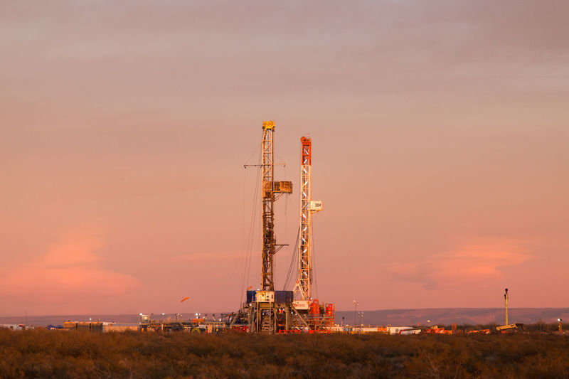 Drilling rig on field against sky