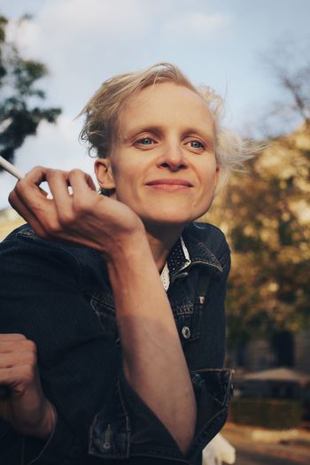 Mid adult woman leaning while holding cigarette