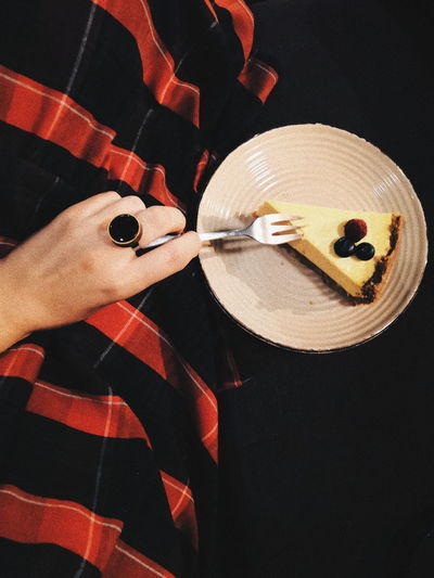 Cropped hand of woman eating pastry in plate