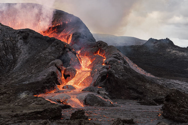 Picturesque view of fagradalsfjall with fast fire and lava under diffusing smoke in mountains with clouds in iceland