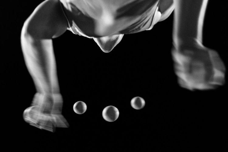 Directly below shot of juggler juggling balls against black background