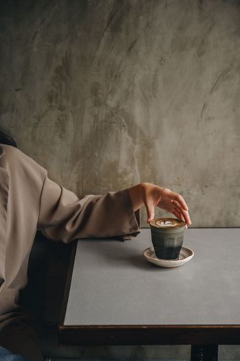 Midsection of woman holding coffee cup at table