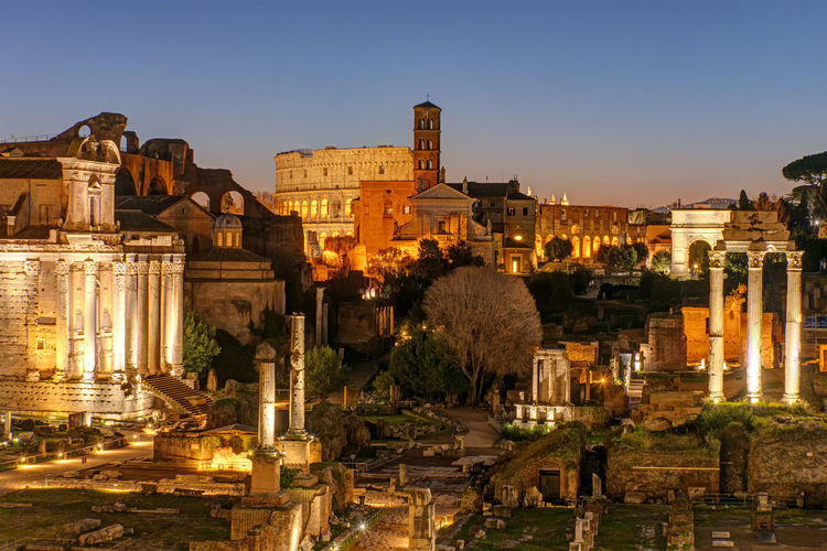 View over the ruins of the roman forum in rome at dawn with the colosseum in the back
