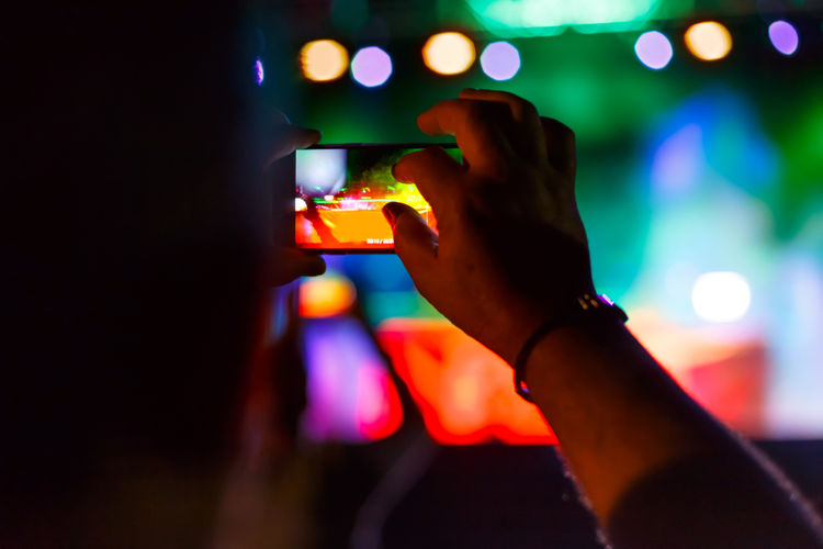 Close-up of man photographing illuminated lights