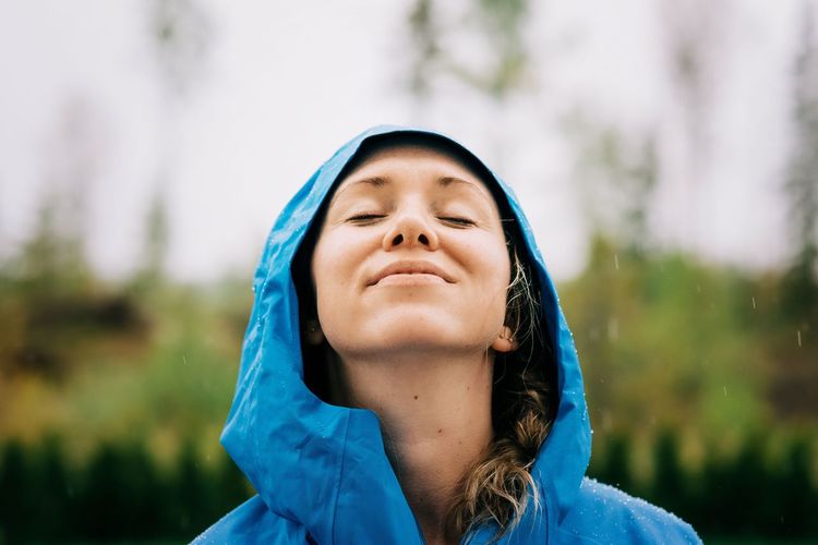 Woman stood in the rain smiling with rain drops on her face