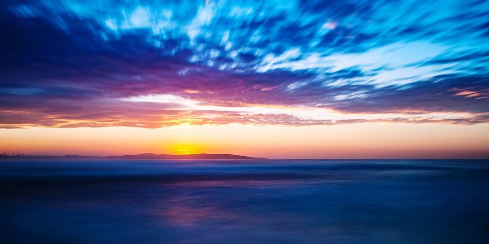Scenic view of sea against dramatic sky during sunset