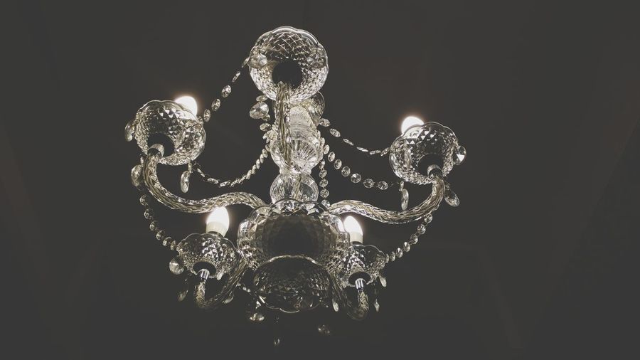 Low angle view of illuminated lighting equipment against black background