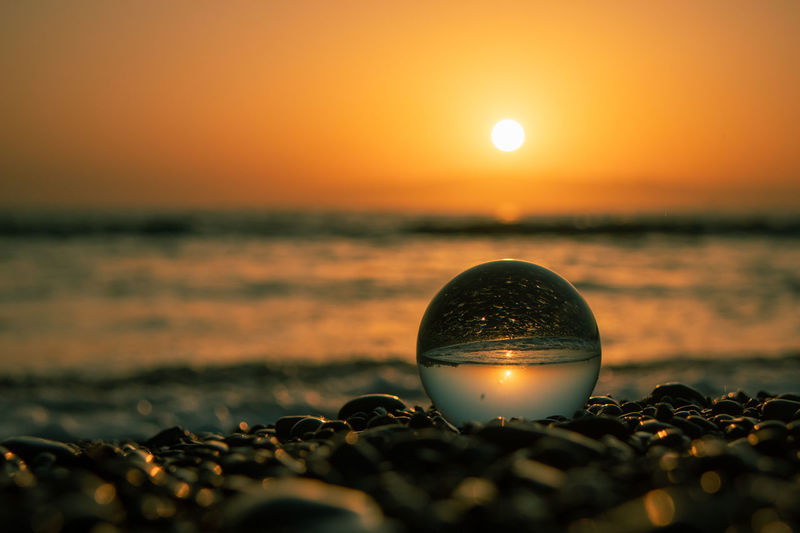 Close-up of crystal ball on beach during sunset