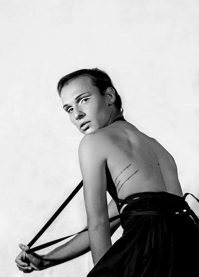 Rear view portrait of man pulling strap against white background
