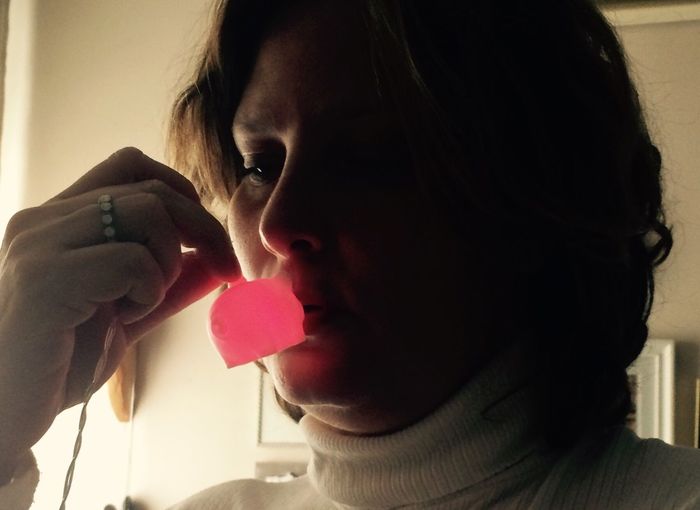 Close-up of woman holding heart shape at home