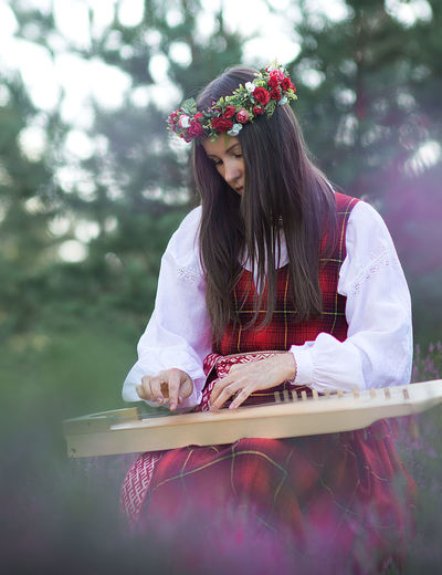 Woman playing string instrument while sitting outdoors