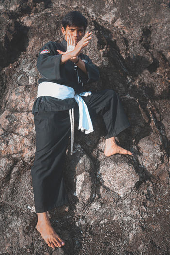 Side view of young man standing on rock